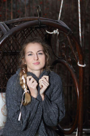 Beautiful blond girl with plait on the swing in the autumn gardenの写真素材