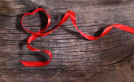 Heart shaped red ribbon on the wooden backgroundの写真素材
