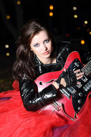 Brunette guitar player girl in the night cityの写真素材
