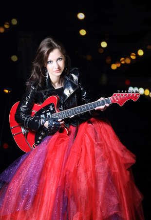 Brunette guitar player girl in the night cityの写真素材