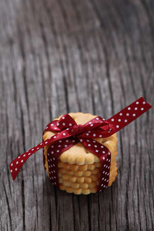 Cookies decorated with dark red polka dots ribbon on the wooden backgroundの写真素材