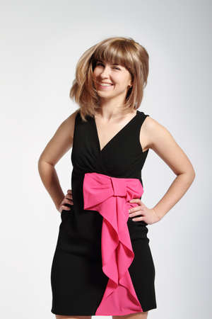Beautiful smiling blonde girl in black dress with pink bowの写真素材