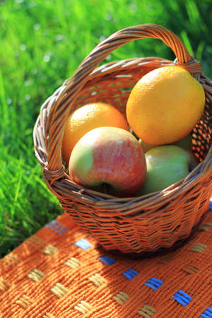 Tasty oranges and apples in the basket on the plaidの写真素材