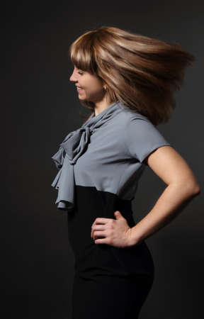 Portrait of young beauty woman with fluttering hair over dark backgroundの写真素材