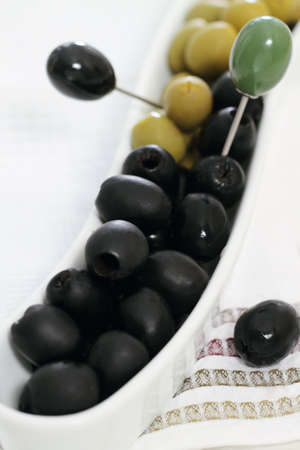 Green and black olives in the bowl on white towelの写真素材