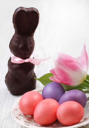 Easter eggs with tulip and chocolate hare on wooden background with space for textの写真素材