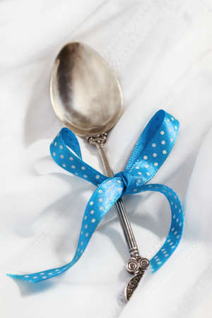 Baby silver spoon with blue bow on whiteの写真素材