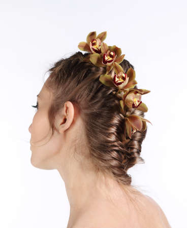 Portrait of the beautiful young blond girl with orchid in her hair
