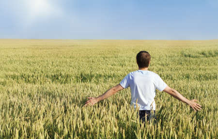 Man standing in wheat field with arms outstretchedの写真素材