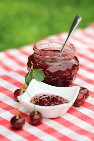 Jar of cherry jam and some cherries on the napkinの写真素材