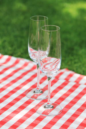 Two empty glasses on the checkered cloth in the gardenの写真素材