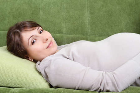 Young pregnant brunette woman relaxing on the sofaの写真素材