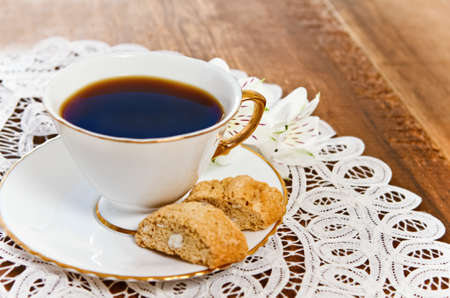 Cookies and coffee with flower on wooden background decorated with white lace napkinの写真素材