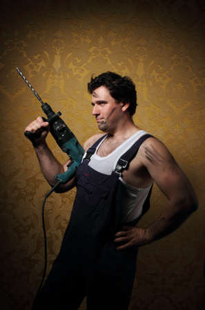 The builder holds the professional puncher-hammer with a drillの写真素材