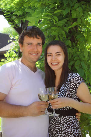 Happy woman and man holding glasses of white wine making a toastの写真素材