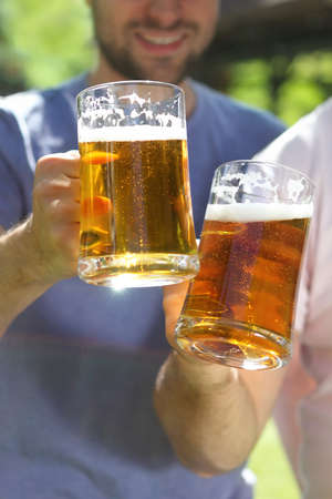 Two men with glasses of the light beer in the gardenの写真素材