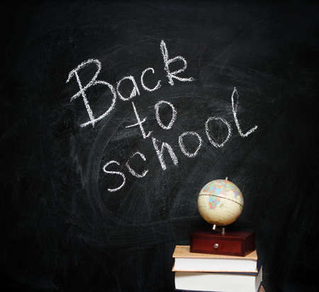 Globe on books against blackboard with textの写真素材