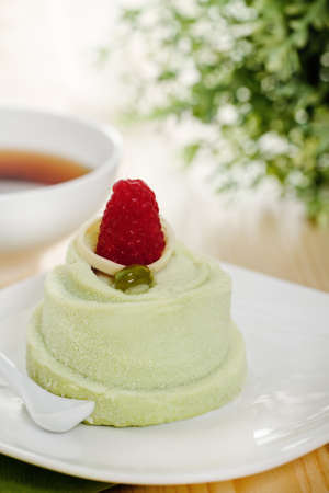 Pistachio cake decorated with a raspberry with coffeeの写真素材