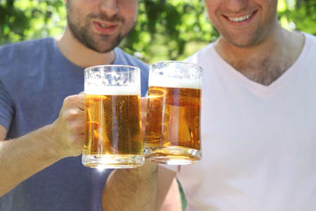 Two men with glasses of the light beer in the gardenの写真素材