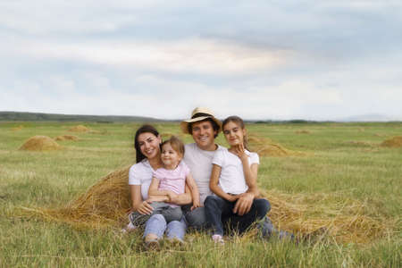 Happy young family with two daughters outdoorsの写真素材