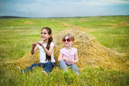 Two happy little sisters having fun in the summer day in fieldの写真素材