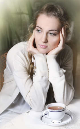 Young blond girl with tea in the cafeの写真素材