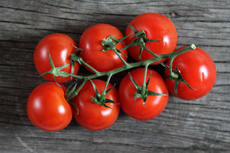 Dewy red tomatoes on the rustic wooden boardの写真素材