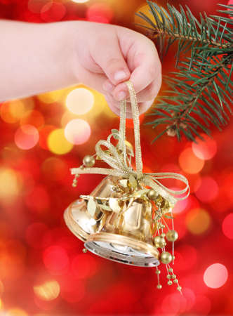 Child holding golden Christmas tree decorations on lights backgroundの写真素材