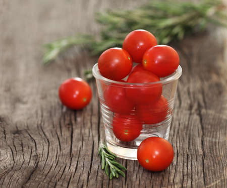 Dewy red tomatoes and basil on the rustic wooden boardの写真素材