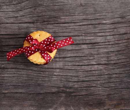 Cookies decorated with dark red polka dots ribbon on the wooden backgroundの写真素材