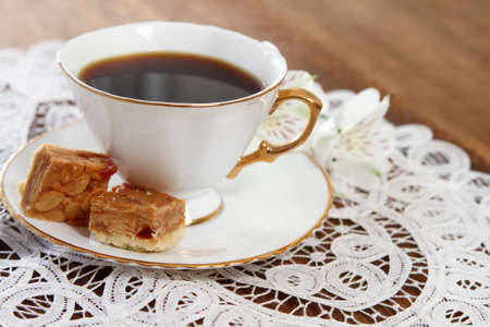 Cookies and coffee with flower on wooden background decorated with white lace napkinの写真素材