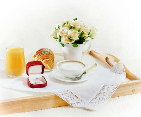 Marriage proposal. An engagement diamond ring with breakfast and bouquet of rosesの写真素材