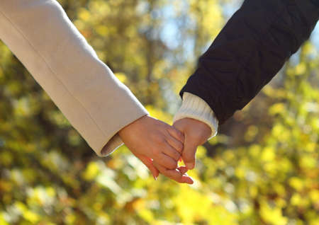 Young couple holding hands in the autumn forest. Close upの写真素材
