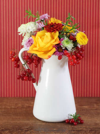 Bouquet of autumn flowers in the iron pot over red backgroundの写真素材