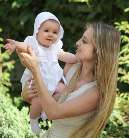 Young mother and her toddler daughter have fun in summer gardenの写真素材