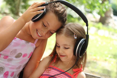 Two sisters listen to the music together outdoorの写真素材