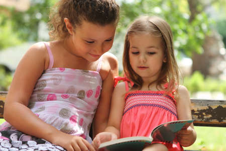 Children reading the book in summer parkの写真素材