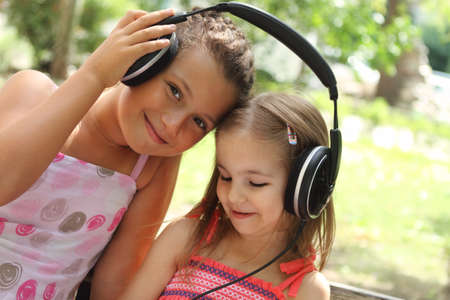 Two sisters listen to the music together outdoorの写真素材