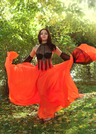 Young brunette girl dancing in the gardenの写真素材