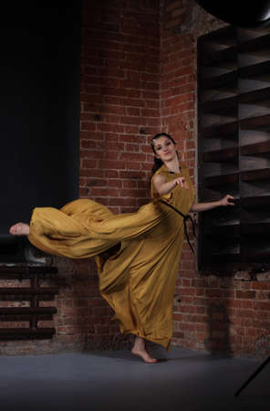 Young brunette woman dancing over brick wallsの写真素材