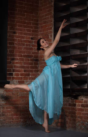 Young brunette woman dancing over brick wallsの写真素材