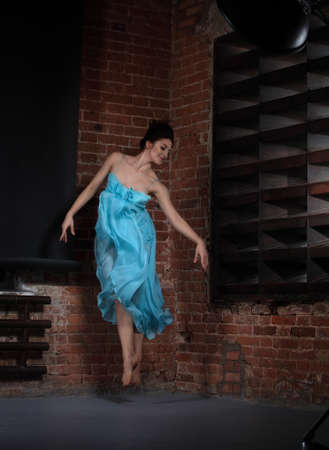 Young brunette woman dancing over brick wallsの写真素材