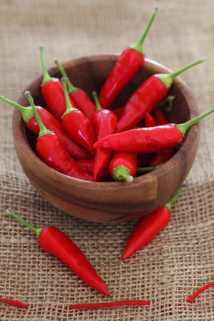 Red hot pepper in wooden bowl over wooden backgroundの写真素材