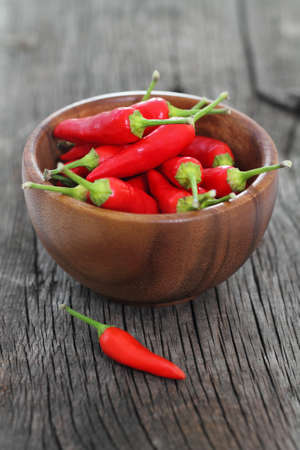 Red hot pepper in wooden bowl over wooden backgroundの写真素材