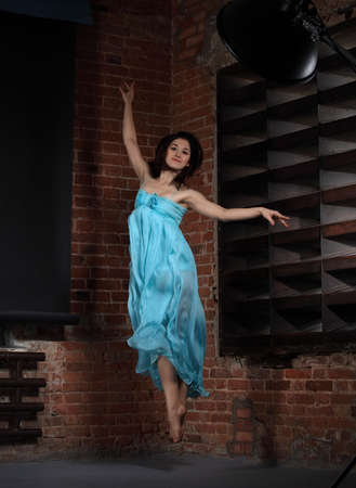 Young brunette woman dancing over brick wallsの写真素材