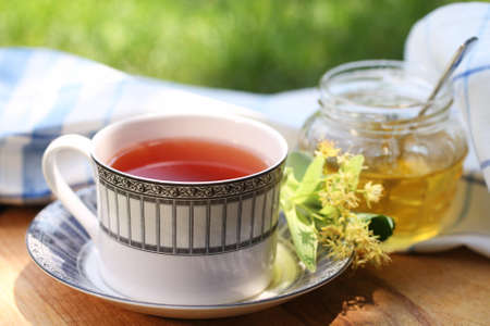 Linden honey in a jar with linden flowers and tea in the gardenの写真素材