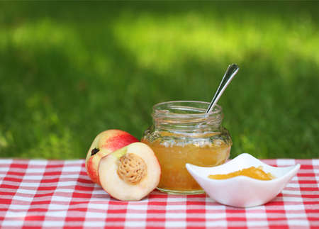 Jar of peach jam and some peaches on the napkinの写真素材