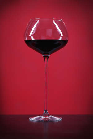 One glass of red whine over red backgroundの写真素材