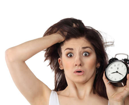 Surprised young brunette woman holding clock in her handin amazementの写真素材