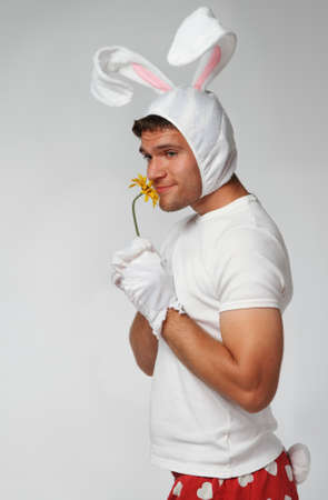 Crazy easter rabbit. Man wearing rabbit suit with flowerの写真素材